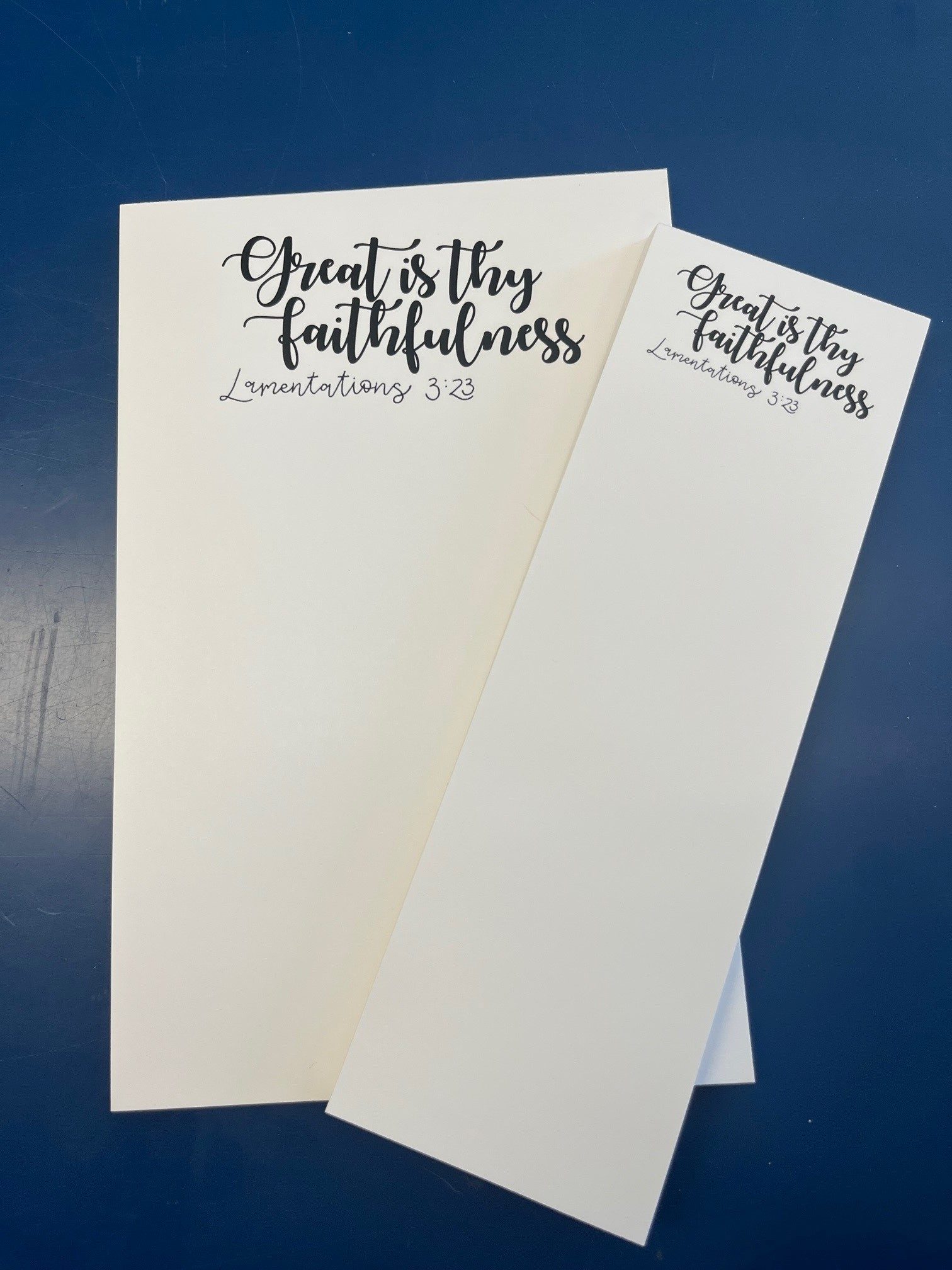 Two sizes of a cream notepad, both reading Great is thy faithfulness, Lamentations 3:23.