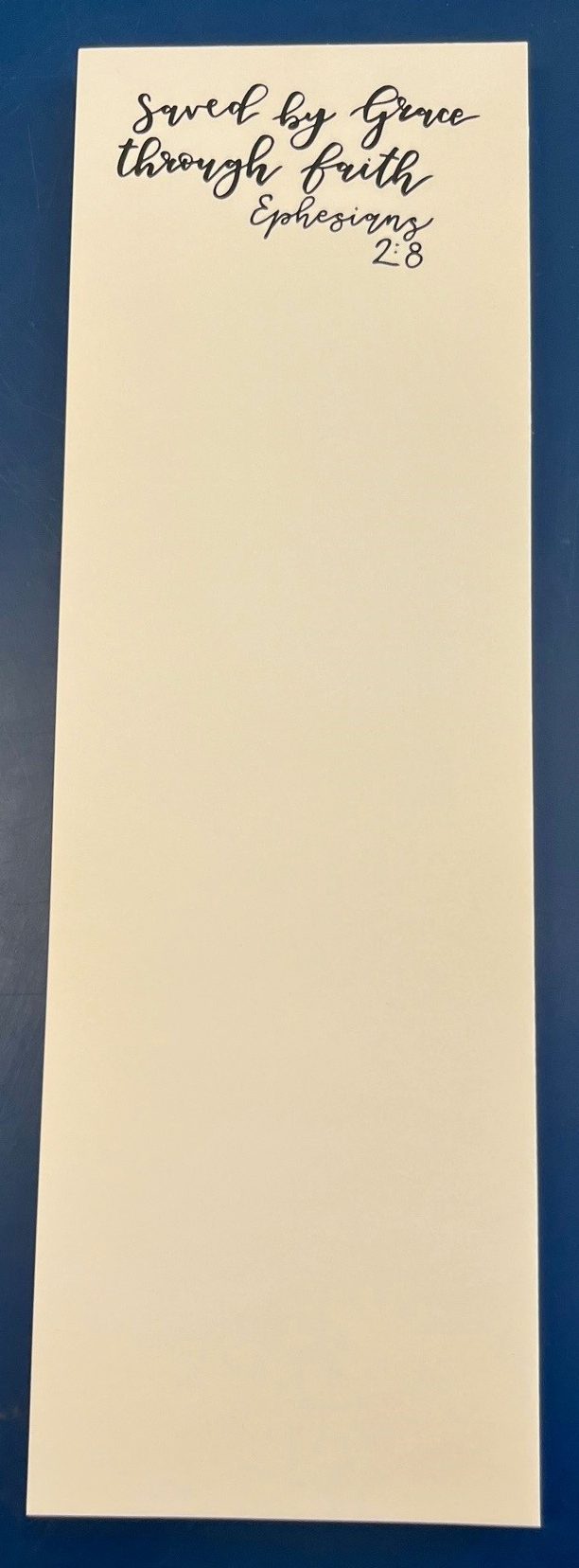 Cream notepad reading Saved by Grace through faith, Ephesians 2:8.